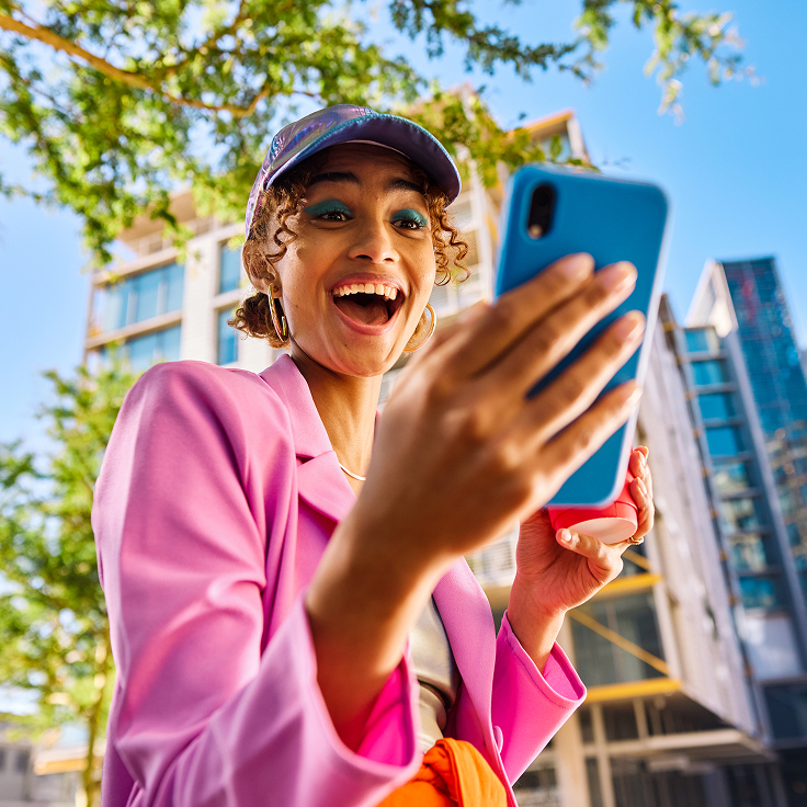 Woman in pink jacket smiling at phone